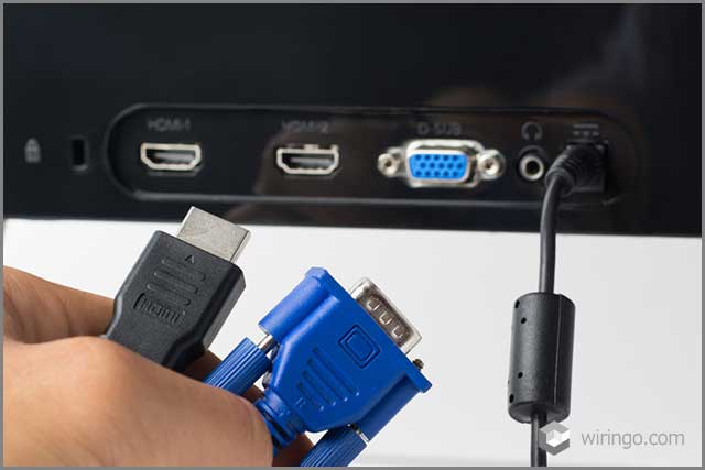 HDMI and VGA cables against a monitor with ports