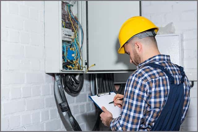 Professional electrician inspecting wires in the electrical box