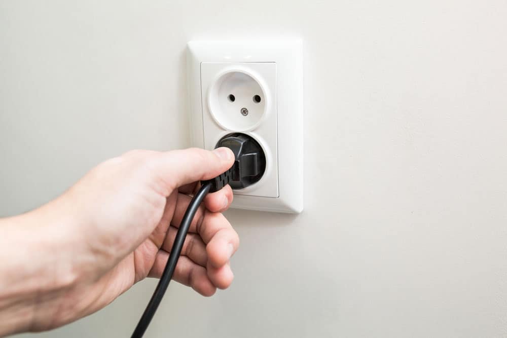 A male hand puts plug in socket