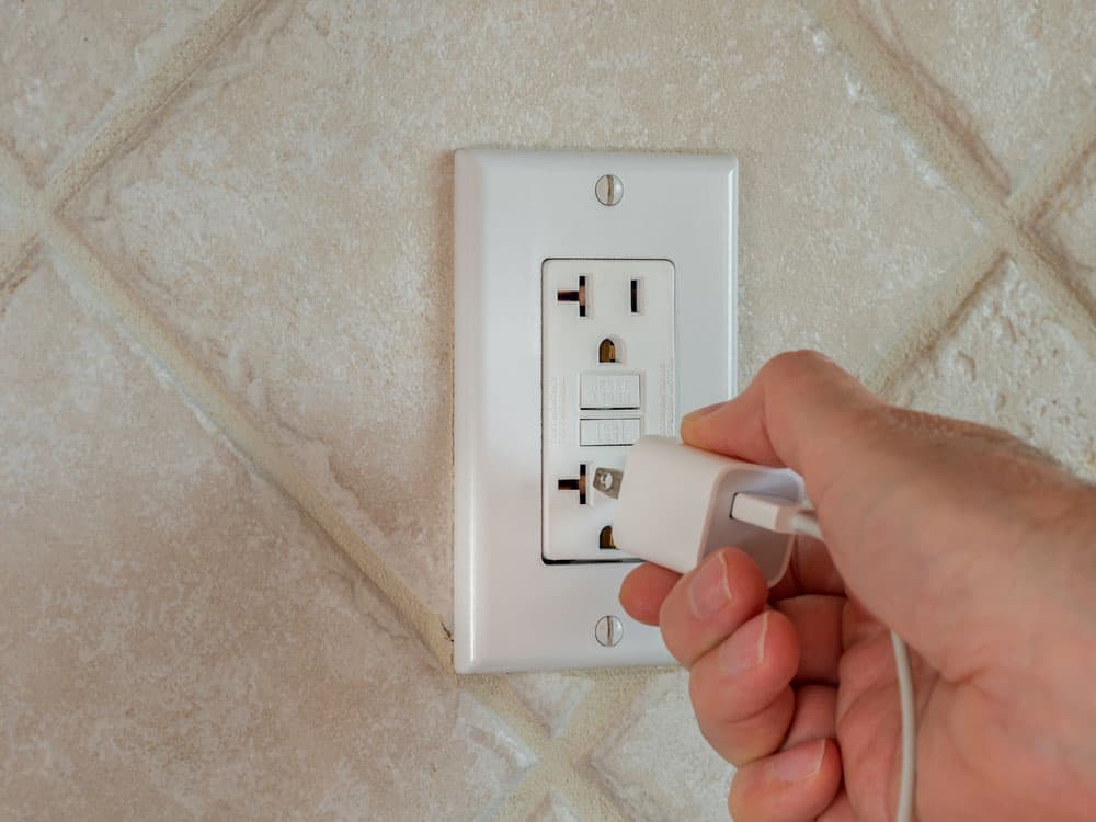 Inserting a mobile charger into a wall plug