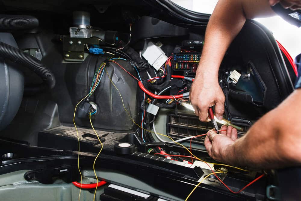 An electrician works with the car’s electrical system
