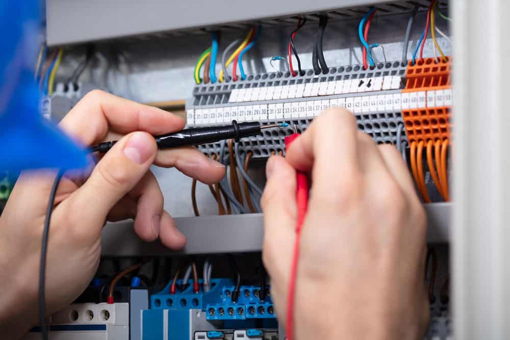 An electrician testing the fuse box with a multimeter