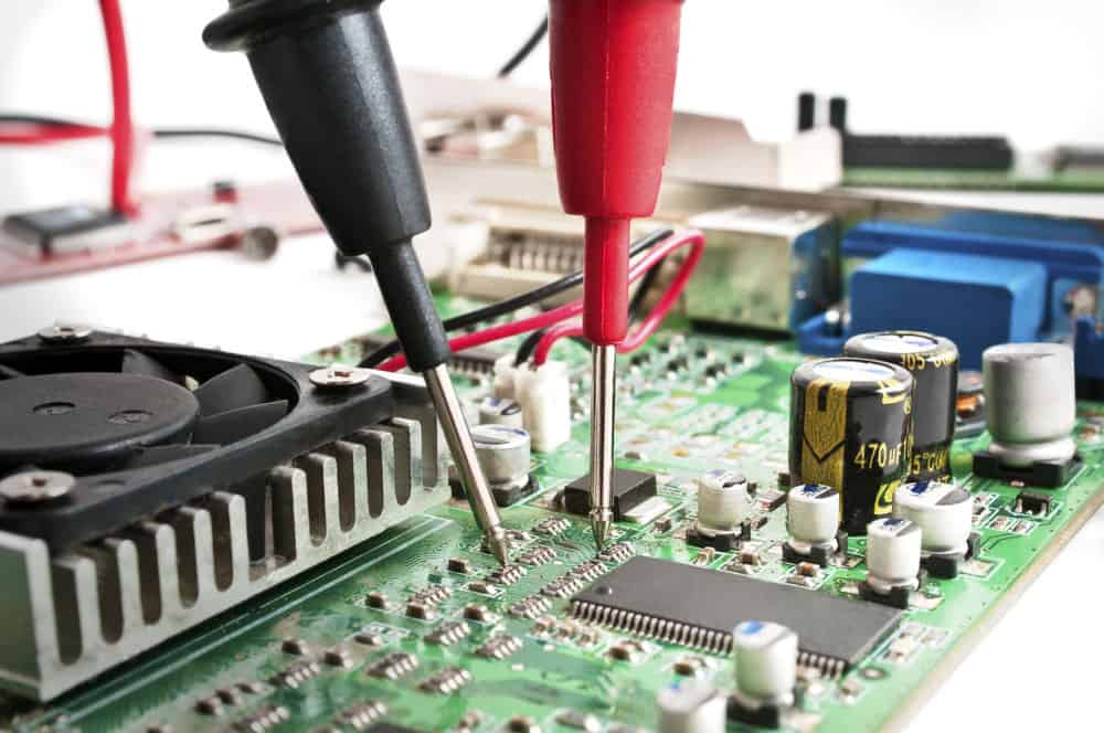 Multimeter probes examining a computer circuit board