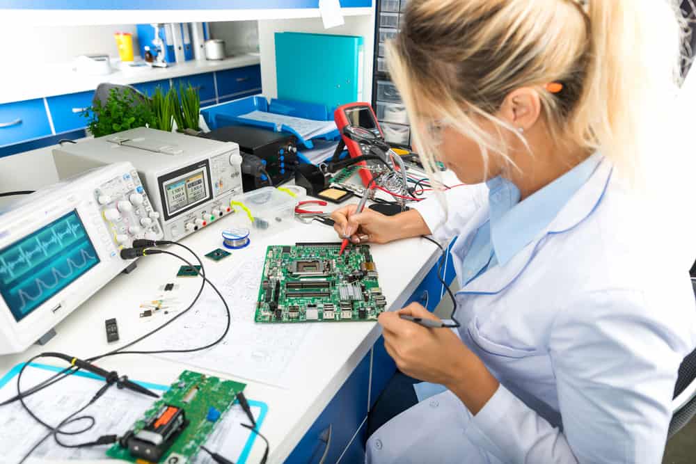 Female digital electronic engineer testing computer PC motherboard in laboratory