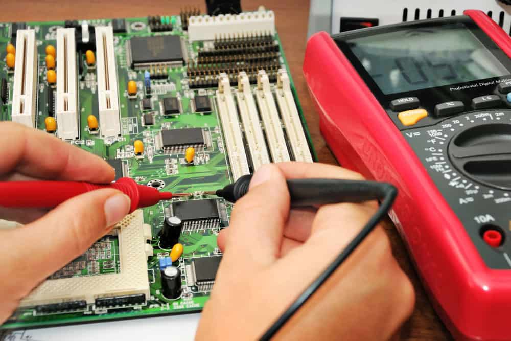 Technician in the lab testing a circuit board with a multimeter